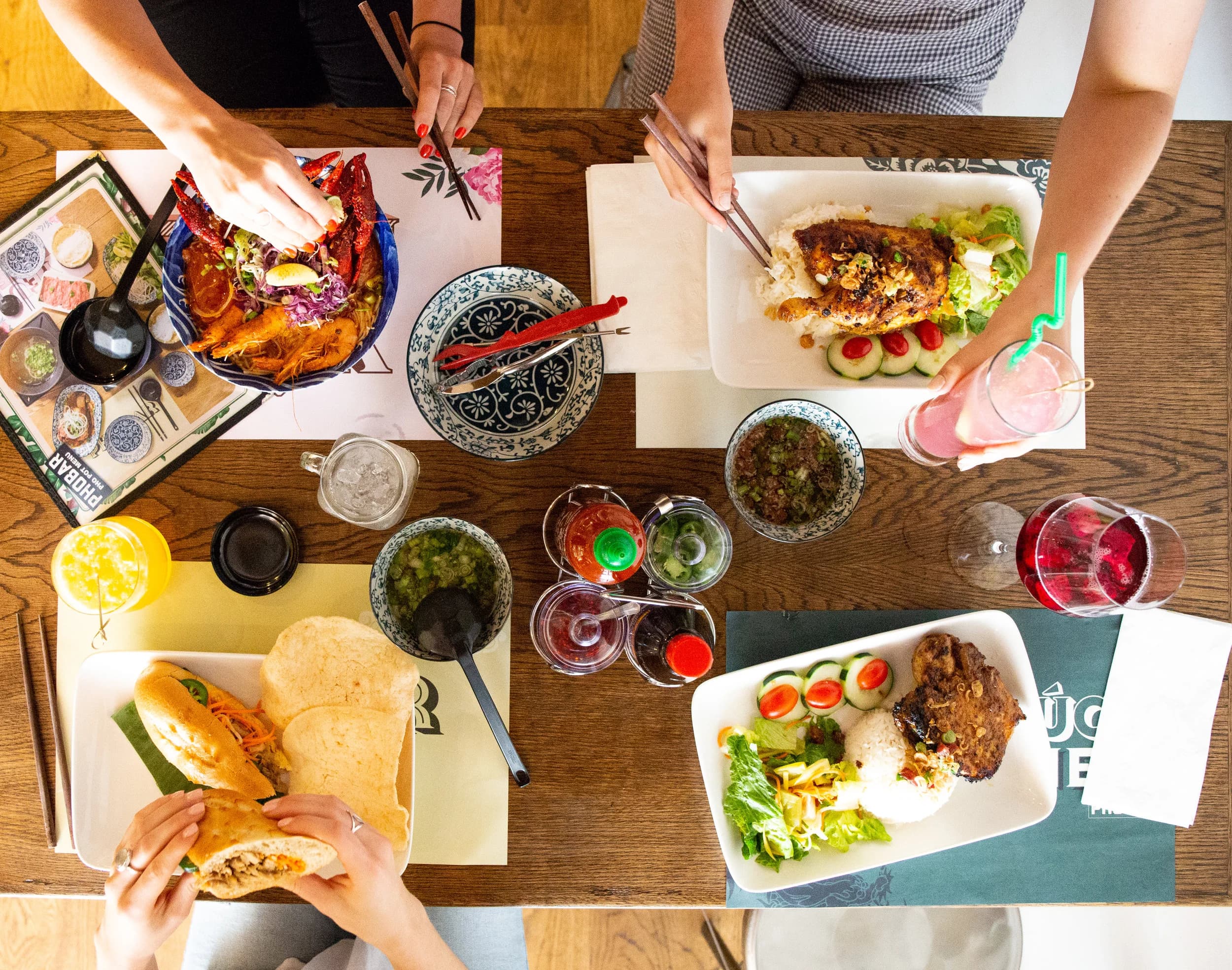 Overhead spread of grilled chicken rice bowl, spring rolls, and drinks